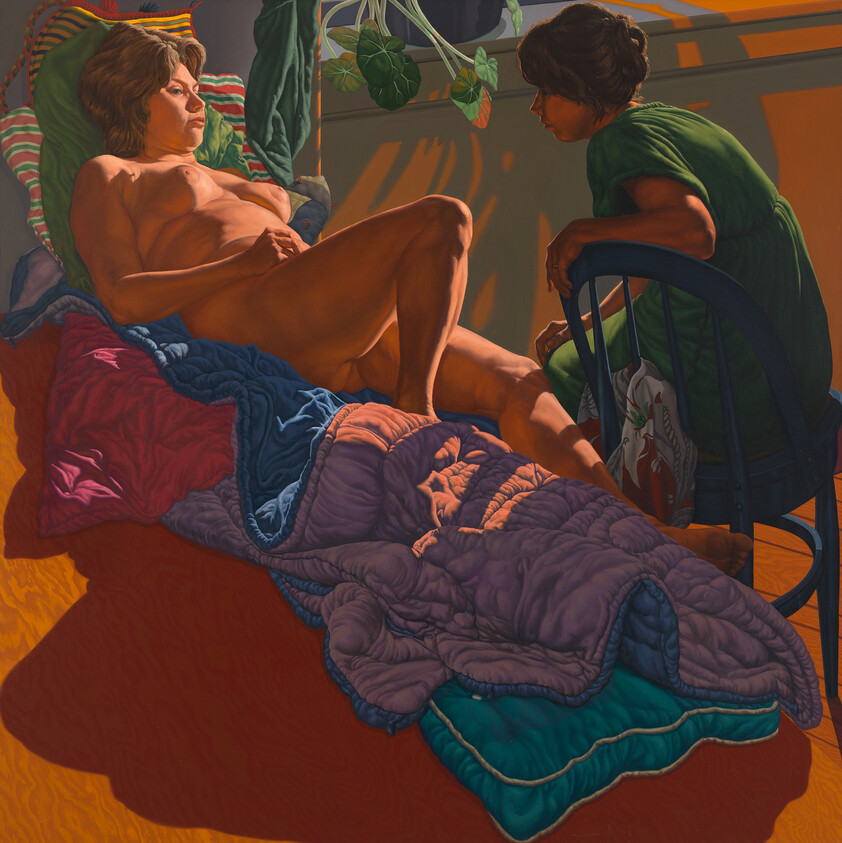 A painting depicting two individuals in an intimate indoor setting. The person on the left is reclining nude on a colorful quilt, propped up by pillows against a wall, with a relaxed posture and a contemplative expression. The person on the right, dressed in a green shirt, is seated on a blue chair, leaning forward with one hand on the reclining person's leg, appearing engaged in conversation. The room is warmly lit, casting shadows on the orange wall, and there's a hanging plant in the upper right corner.