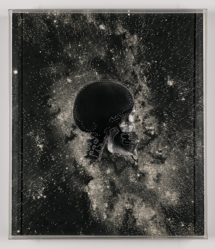 A dark human skull silhouette floats against a dense, star-filled galaxy background.