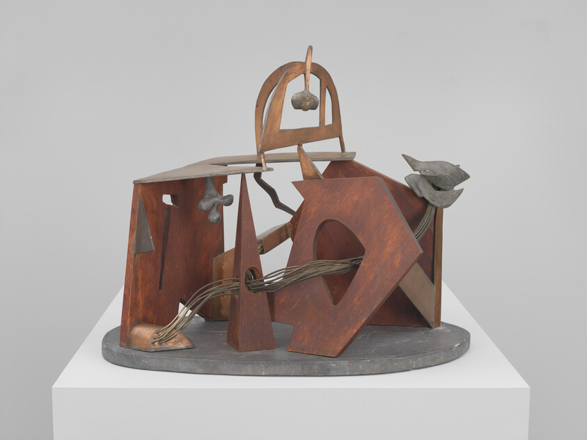 Abstract metal sculpture with rust-colored geometric shapes and intertwined wires on a pedestal.