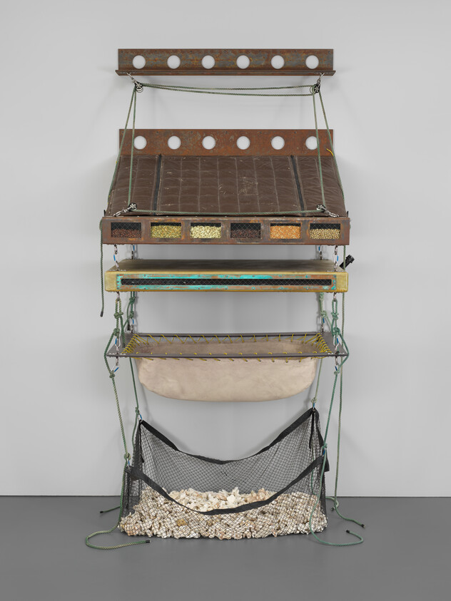 A vertical hanging shelving unit with nets and compartments containing small white stones.
