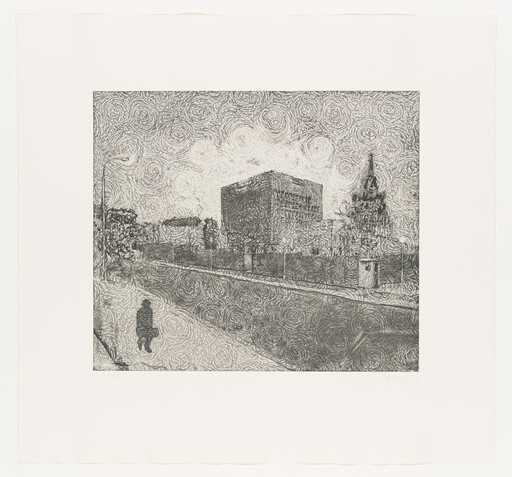 A lone person sitting on a sidewalk near a large blocky building and church spire.