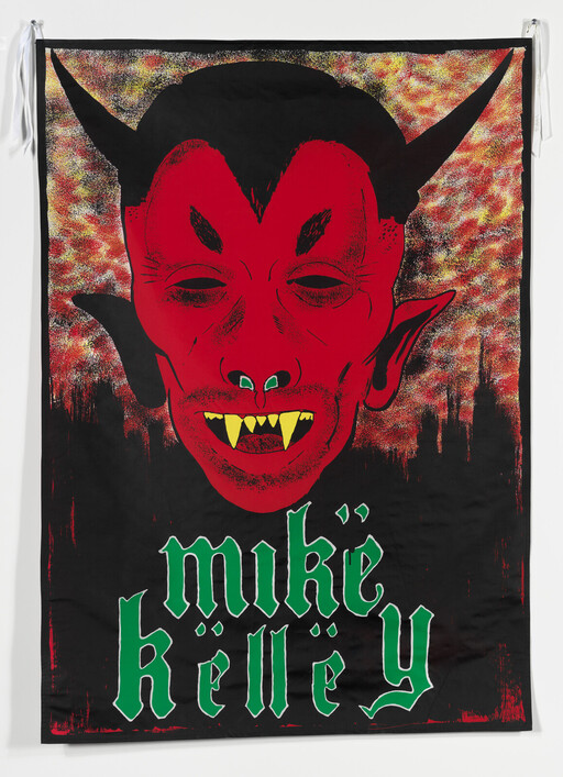 A large red devil face with horns and yellow fangs over green "Mike Kelley" text.