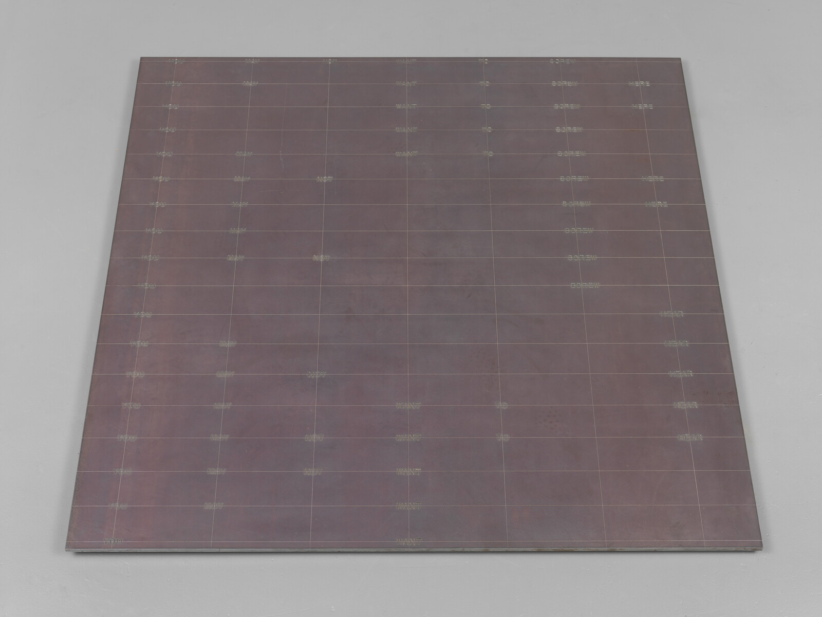 Large square metal panel with faint grid lines laid flat on a light floor.
