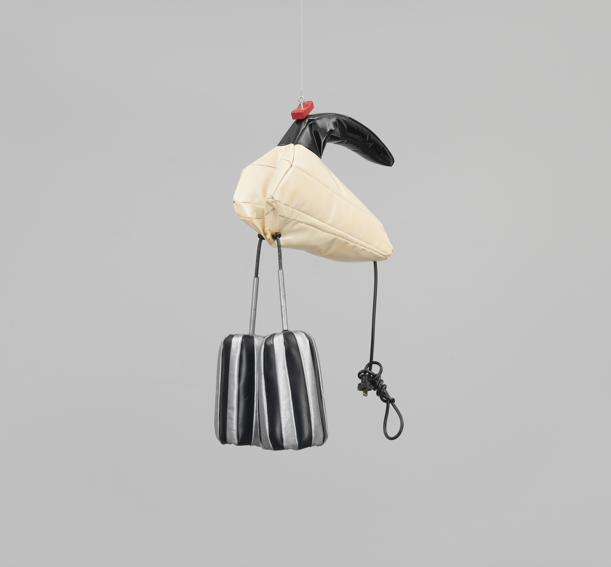 Inflatable bird-shaped sculpture with a black beak and striped legs, hanging from a wire.