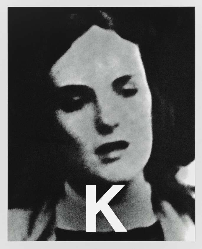 Portrait of a woman's face in high-contrast black and white with a large letter K.