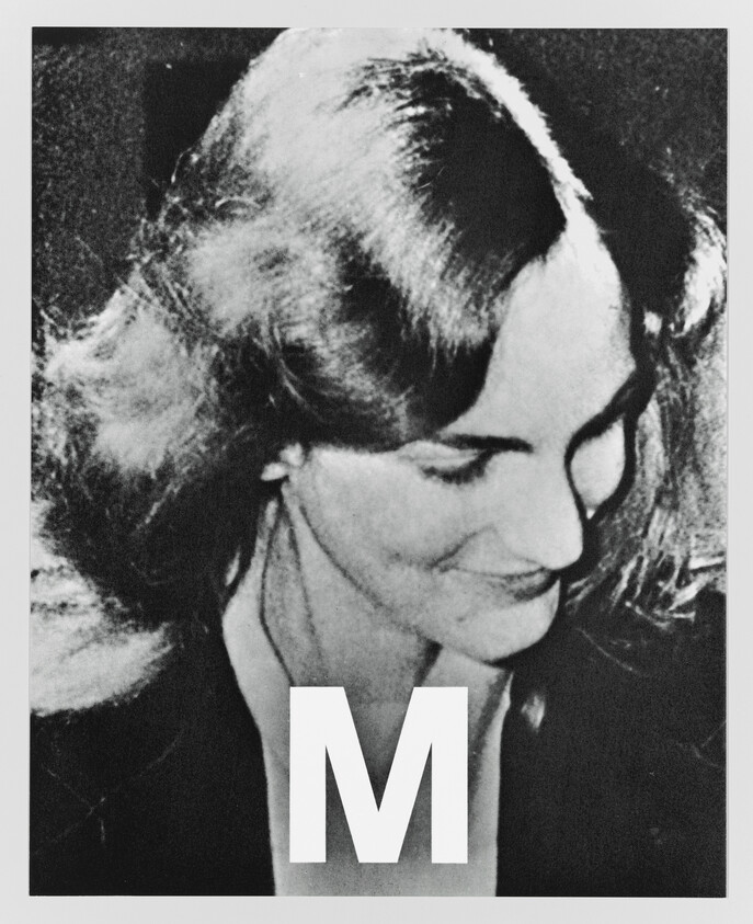 A woman looks down and smiles while a large letter "M" appears at the bottom.