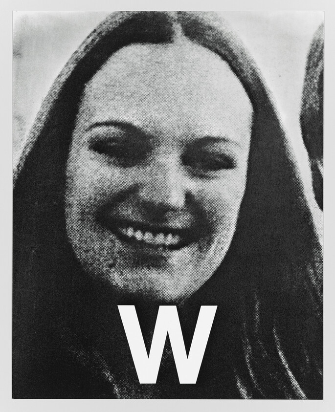 Young woman smiling at camera with a large letter W printed at the bottom.