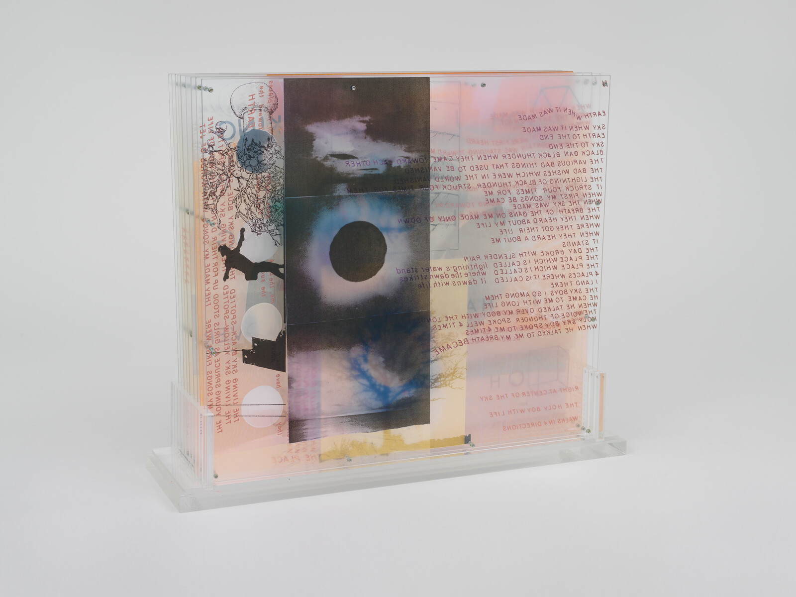 Layered translucent acrylic panels display photographs, text, and silhouettes forming a collage artwork.