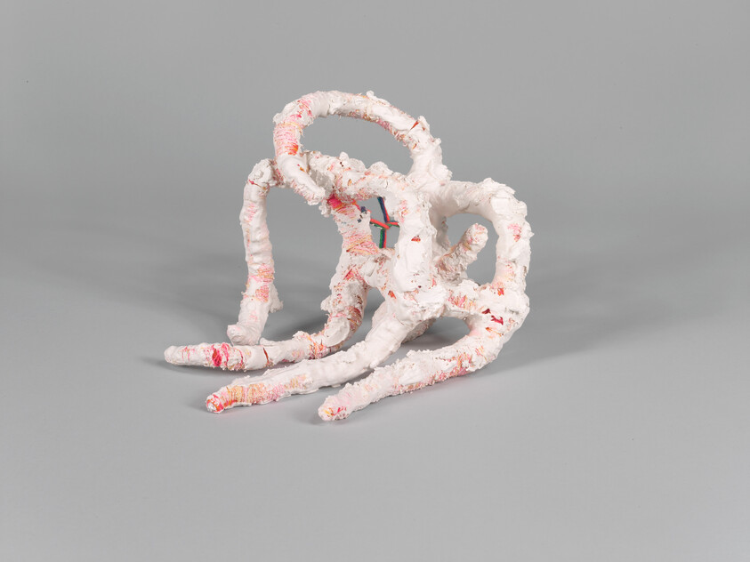 A white textured abstract sculpture with pink accents and looping, tentacle-like forms.