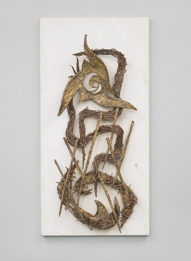 Bronze and thorny vine sculpture forming swirling shapes mounted on a white rectangular panel.