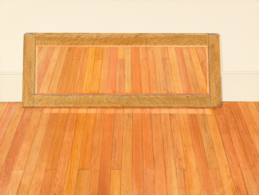 A rectangular wooden frame lying flat on a hardwood floor, creating an illusion of a painting of the floor within its borders.