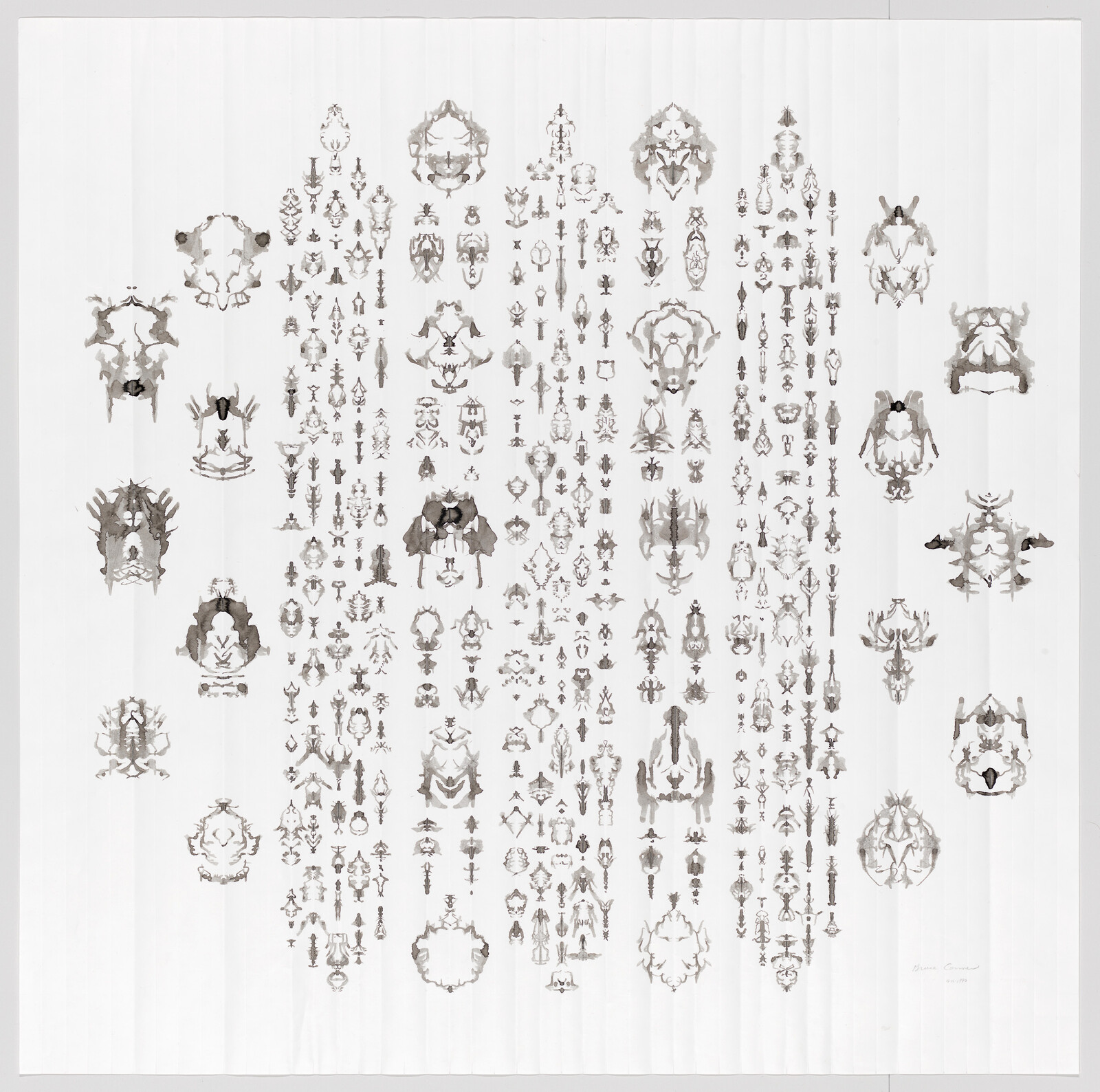 Many small symmetrical inkblot shapes are arranged in a loose circular grid on a white background.