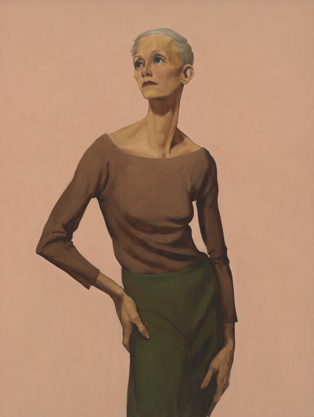 An older woman with short white hair stands with one hand on her hip, looking upward.
