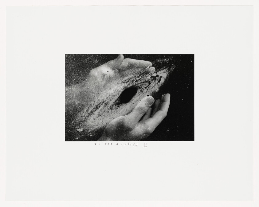 Two hands cupping a swirling galaxy or black hole made of dust and stars.