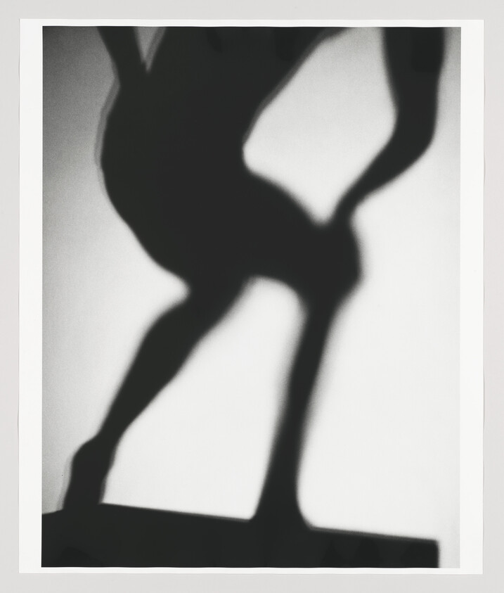 A dark shadow silhouette of a person in a dynamic pose with bent legs and hands on hips.
