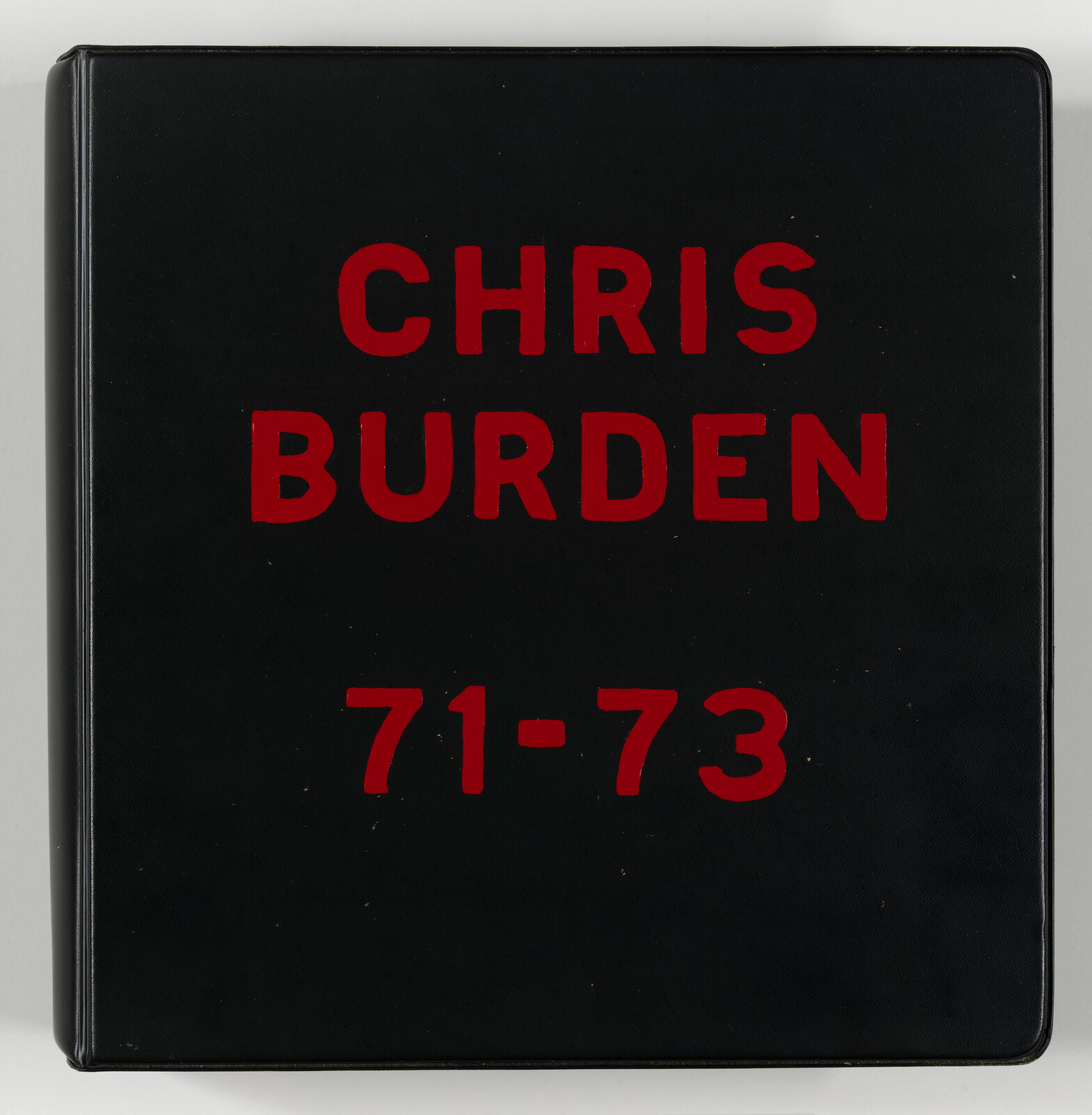 A black hardcover book with "CHRIS BURDEN 71-73" printed in bold red letters on the cover.