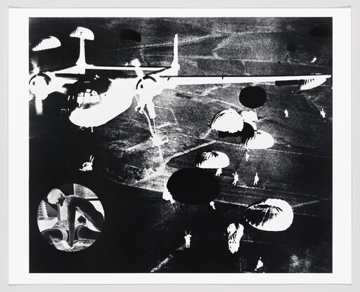 Large transport aircraft releasing paratroopers with multiple parachutes descending over dark terrain.