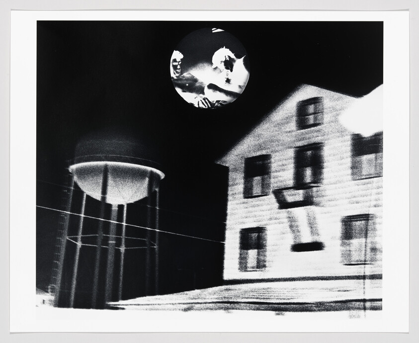 A house and tall water tower under a dark sky with a circular moon showing ghostly faces.