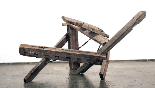 A large wooden frame with chains resting on a tiled floor.
