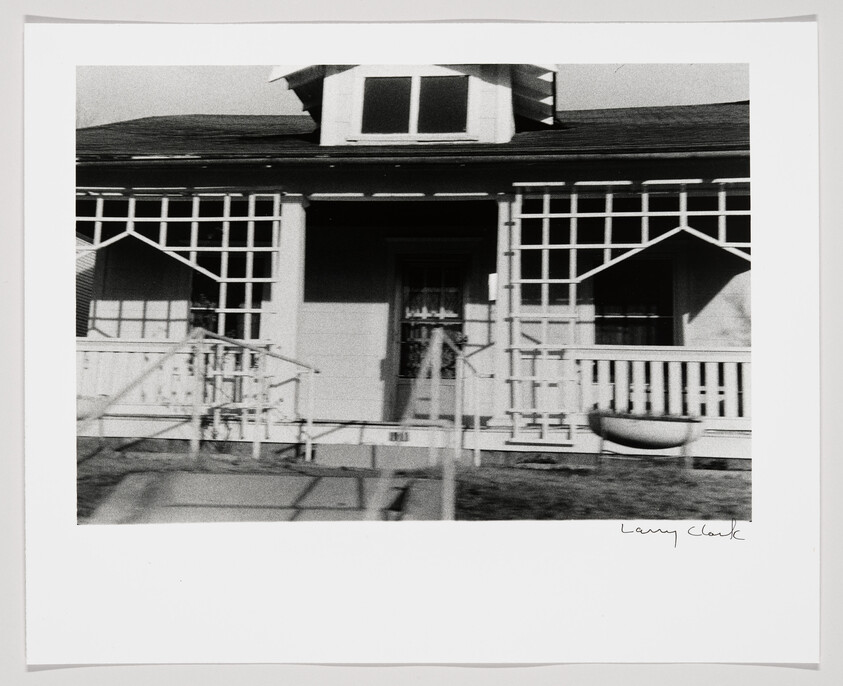 Front porch of a small house with latticework, railing, and steps leading to the door.