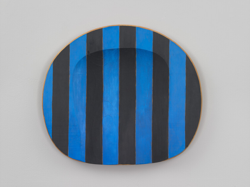 Round wall-mounted artwork with alternating vertical blue and black stripes.