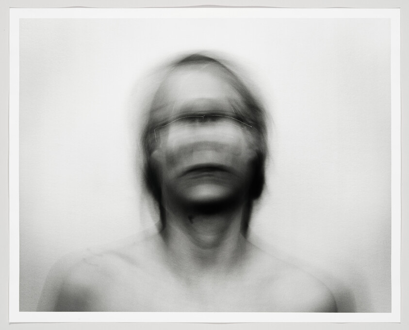 Blurred portrait of a person shaking their head, creating ghostly multiple facial outlines.