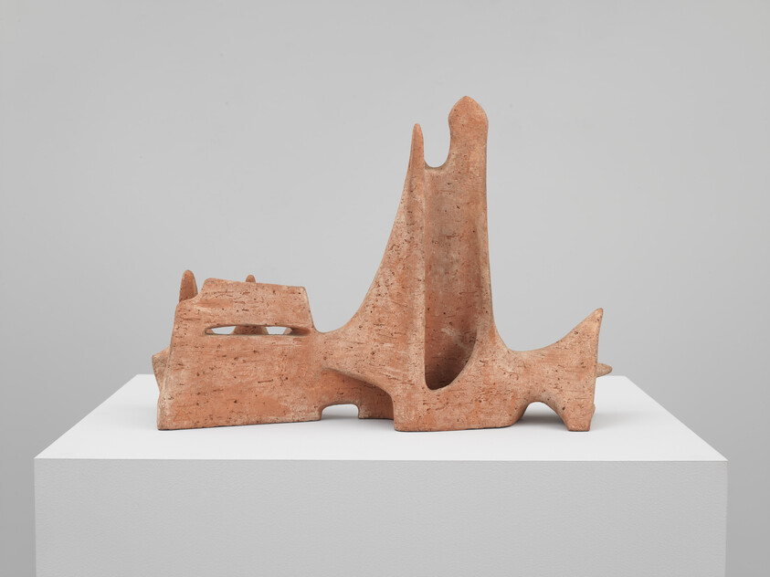 Abstract terracotta sculpture with tall curved forms and hollow openings displayed on a white pedestal.