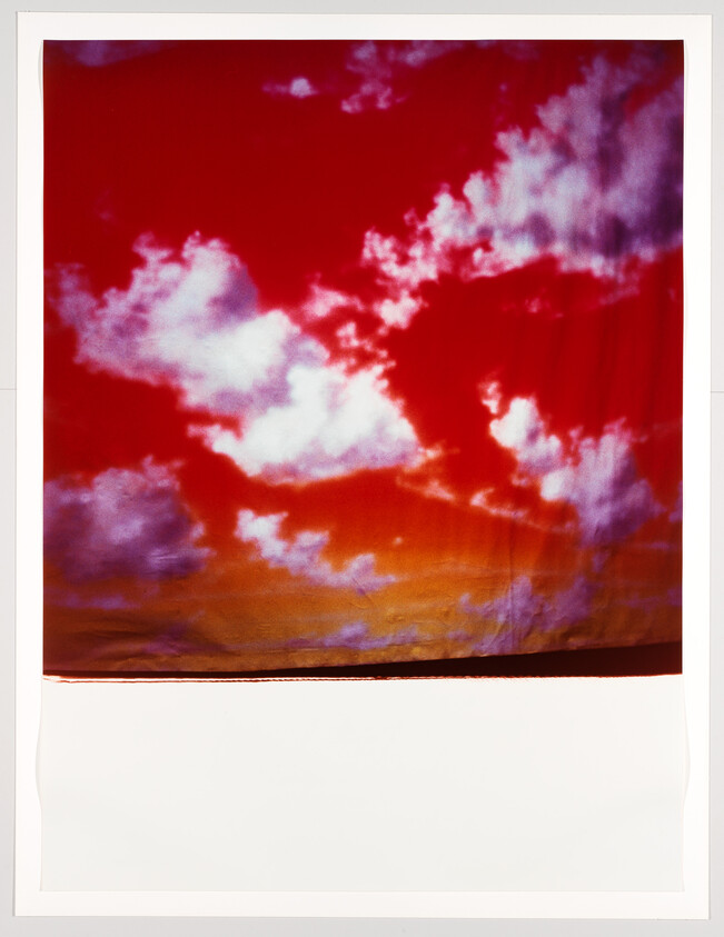 Bright red sky with white clouds and orange horizon over a wide white foreground.