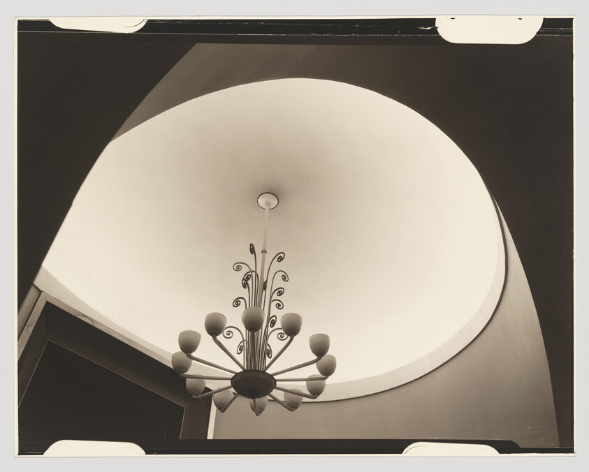 A decorative chandelier hangs beneath a large circular domed ceiling with soft lighting.