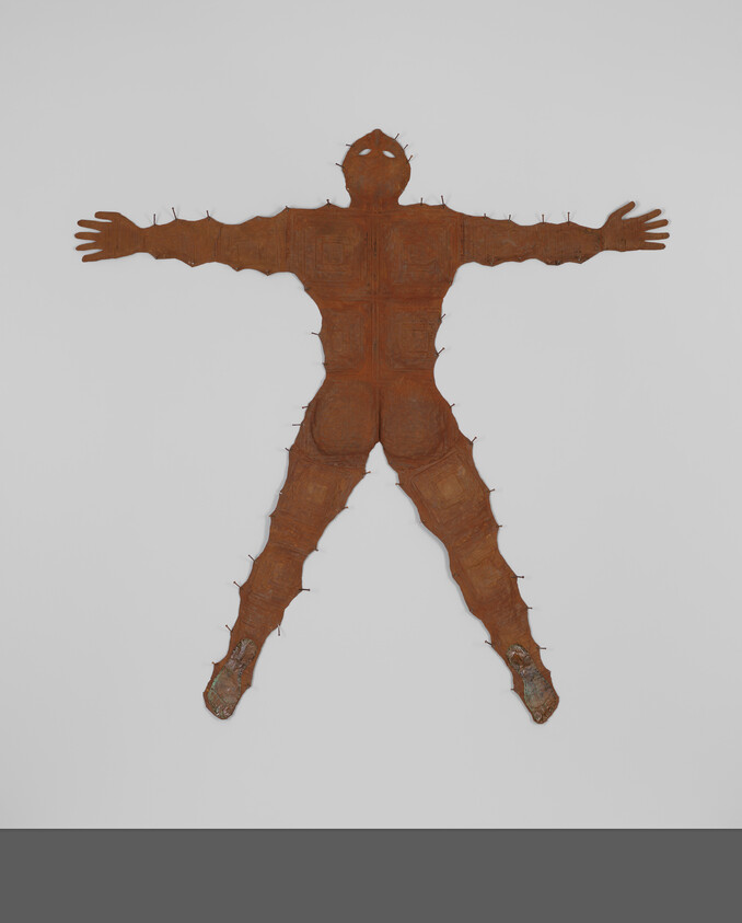 Rust-colored metal human silhouette with outstretched arms and nails along its edges.