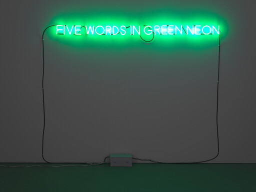 A green neon sign mounted on a wall reads 'FIVE WORDS IN GREEN NEON' above an electrical box.