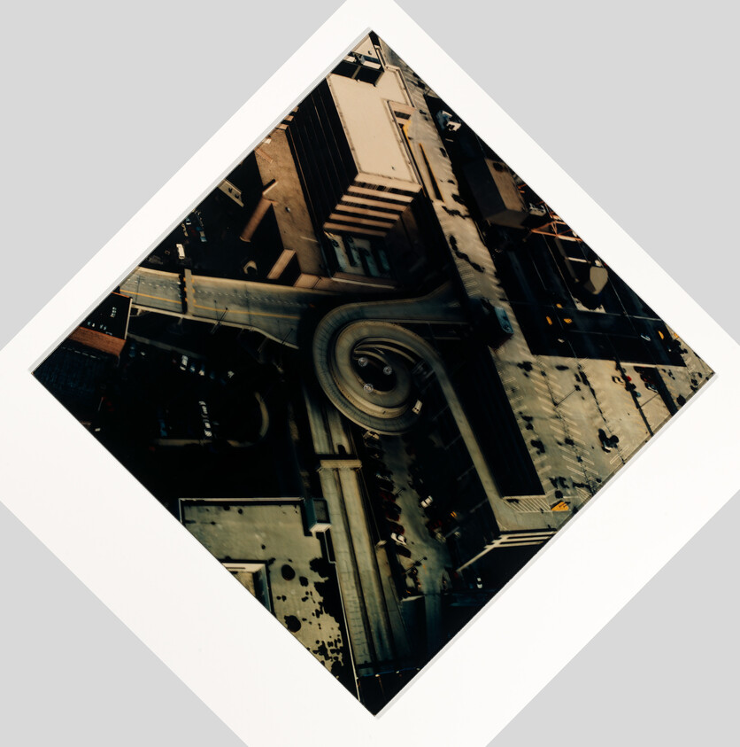 Aerial view of a city block with a circular ramp and surrounding rooftops.