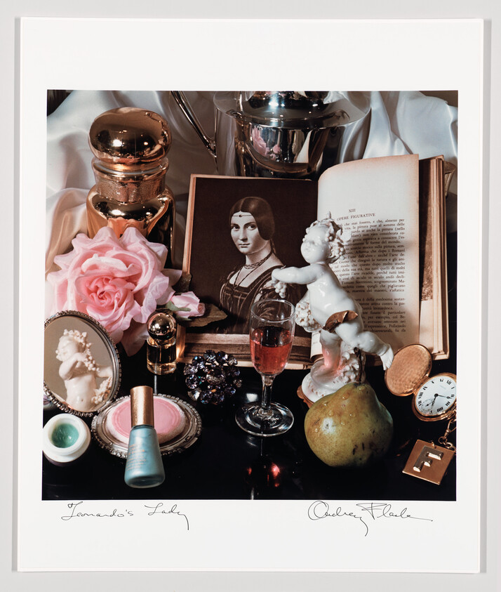 Still life arrangement with a vintage portrait, porcelain cherub, open book, pink rose, glass, and pear.