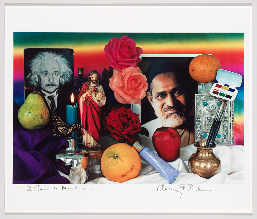 Still-life altar with portraits, roses, fruit, a lit candle, and assorted art and religious objects.