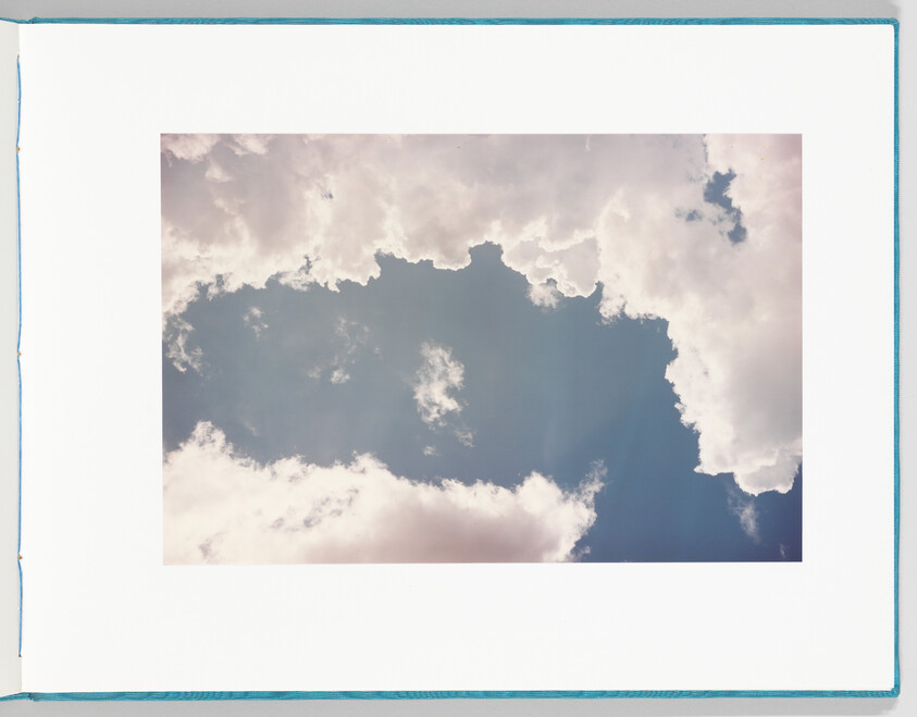 Large white clouds framing a bright blue patch of sky with sunlit edges.