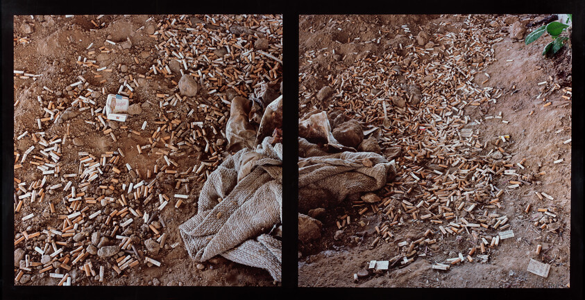 Ground littered with hundreds of cigarette butts scattered around a dirty blanket.