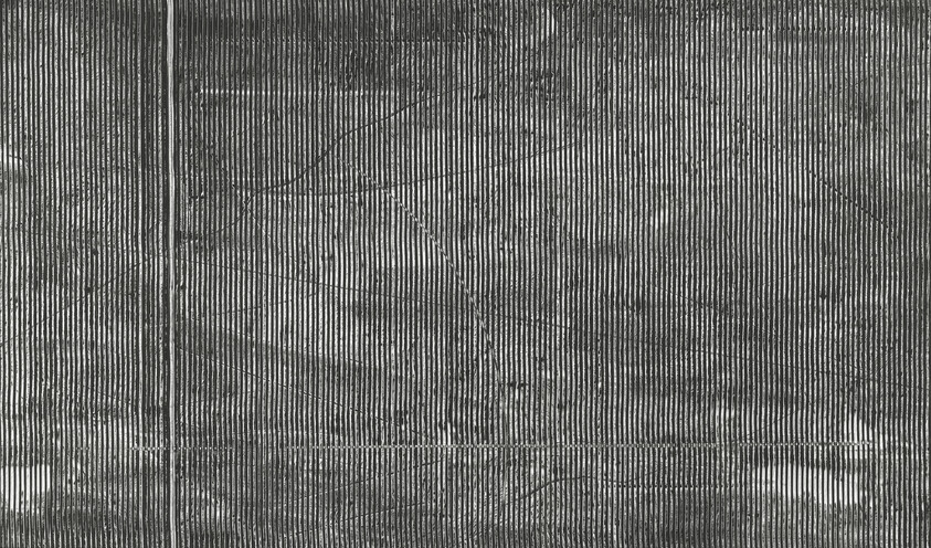 Corrugated metal panel with vertical ridges, scratches, and a horizontal seam near bottom.