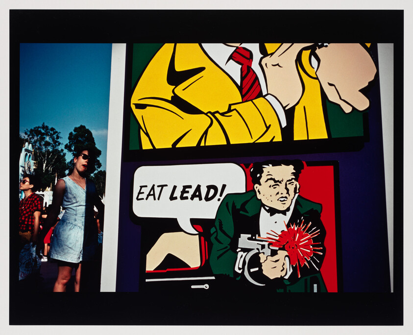 A comic-style panel shows a suited man firing a gun with a speech bubble saying "EAT LEAD!".