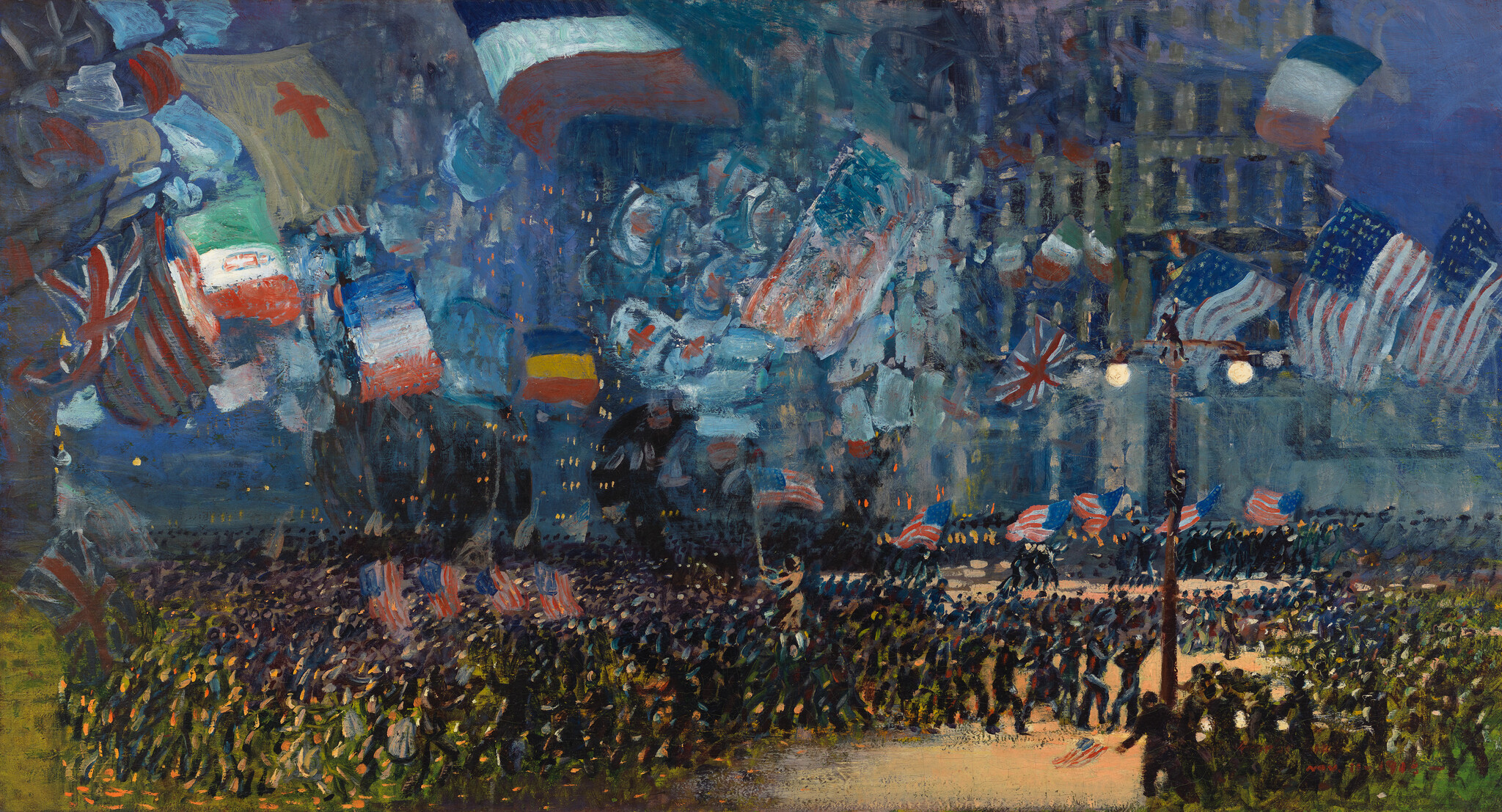 Crowd gathers under streetlights with various flags waving, creating a lively and colorful scene.