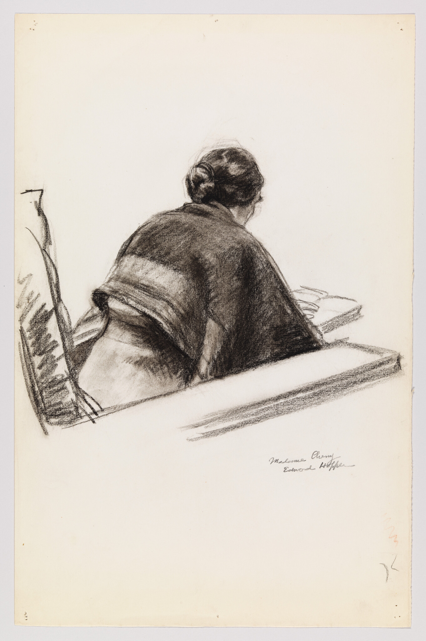 Woman with hair in a bun sits at a desk, leaning forward over papers.