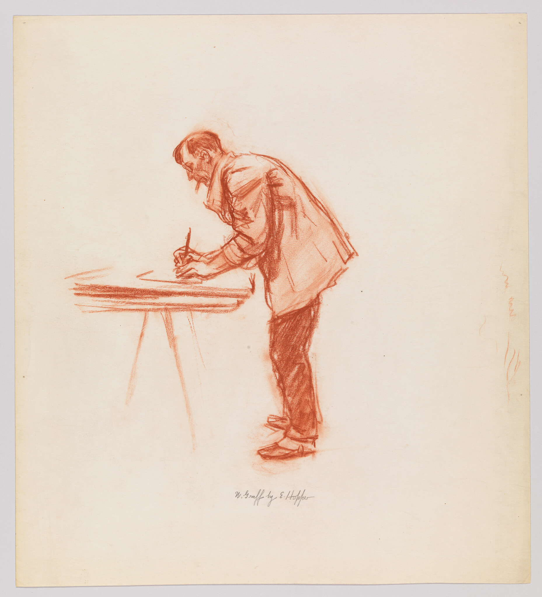 A man leaning over a table writing or sketching with a pencil.