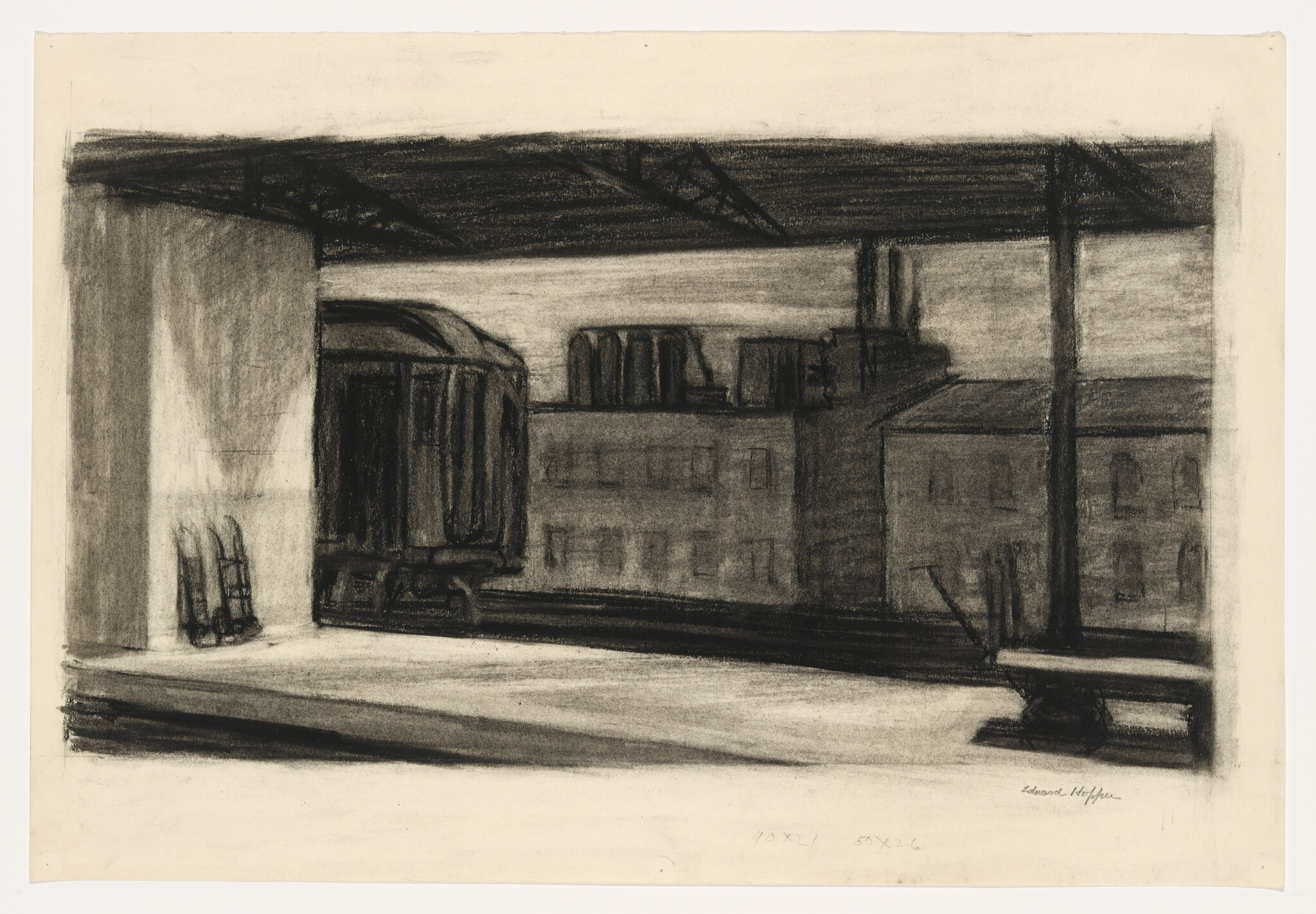 An empty elevated train platform with a parked railcar and industrial buildings in the background.