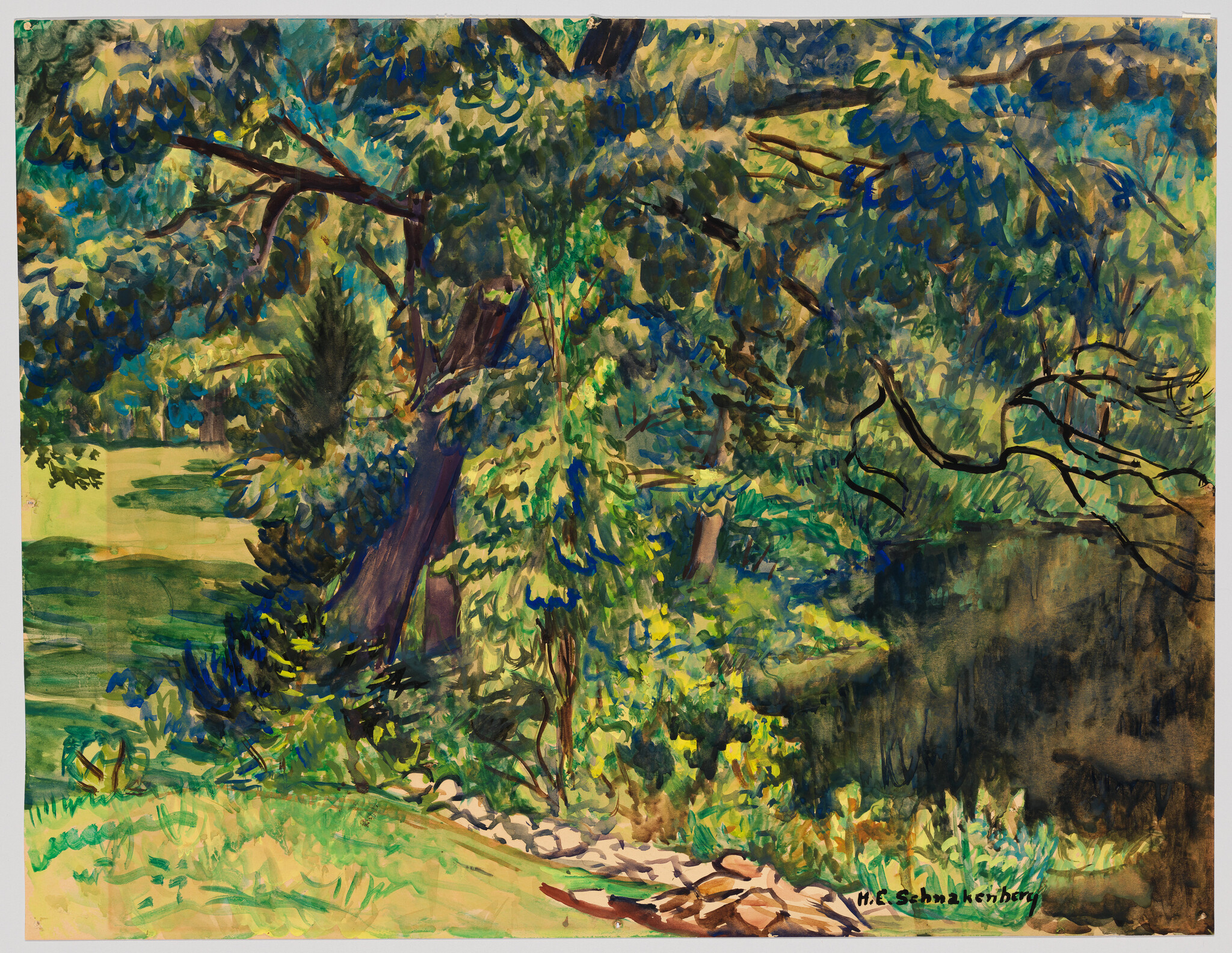 An elderly bearded man sits cross-legged on a chair, staring intently toward the camera.