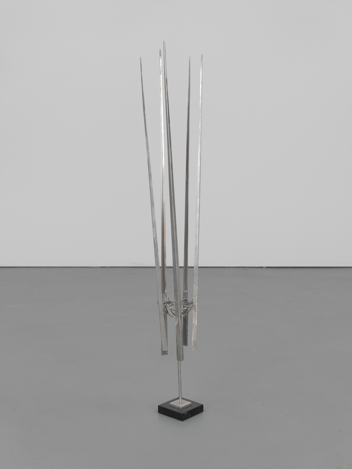 A freestanding metal sculpture with five tall, thin vertical rods mounted on a square base.