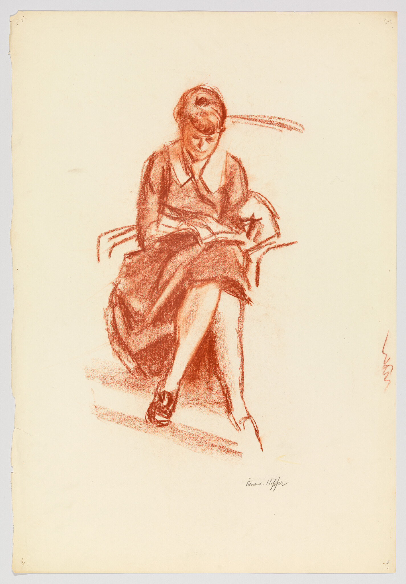 A woman in a dress sits in a chair reading a book with legs crossed.