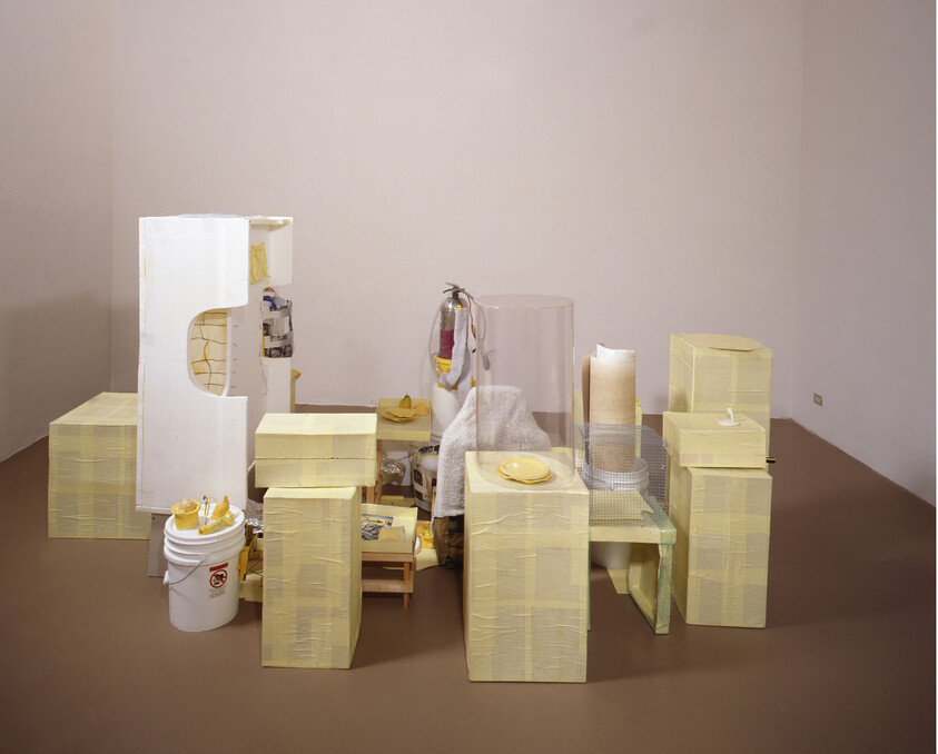 Several household furniture and objects wrapped in yellow tape arranged in an empty room.