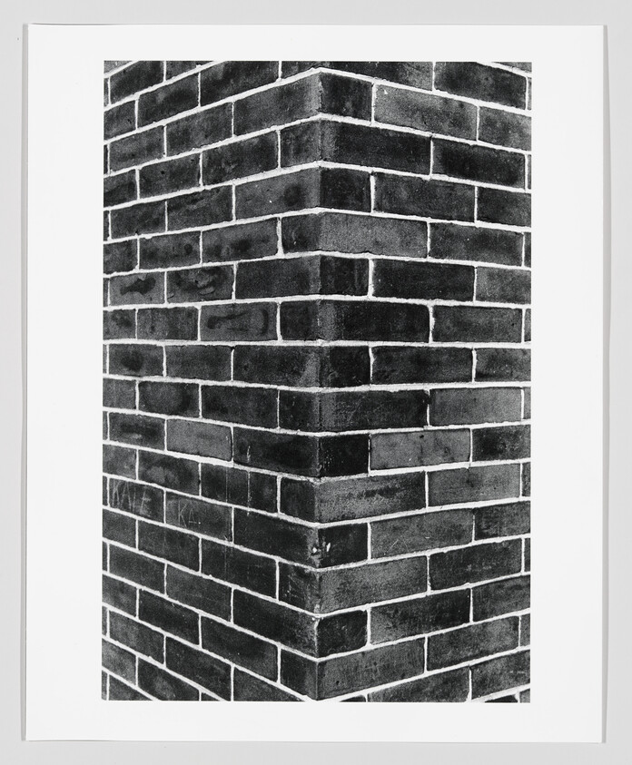 Framed black-and-white print showing a corner of a brick wall with clear mortar lines.