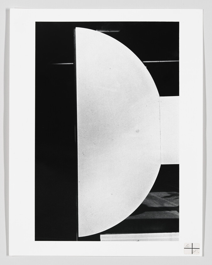 Large white semicircular shape centered against a black rectangular background in a high-contrast abstract composition.