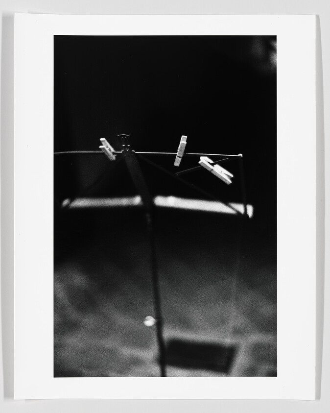 Clothespins clipped to the top of a folding drying rack against a dark background.