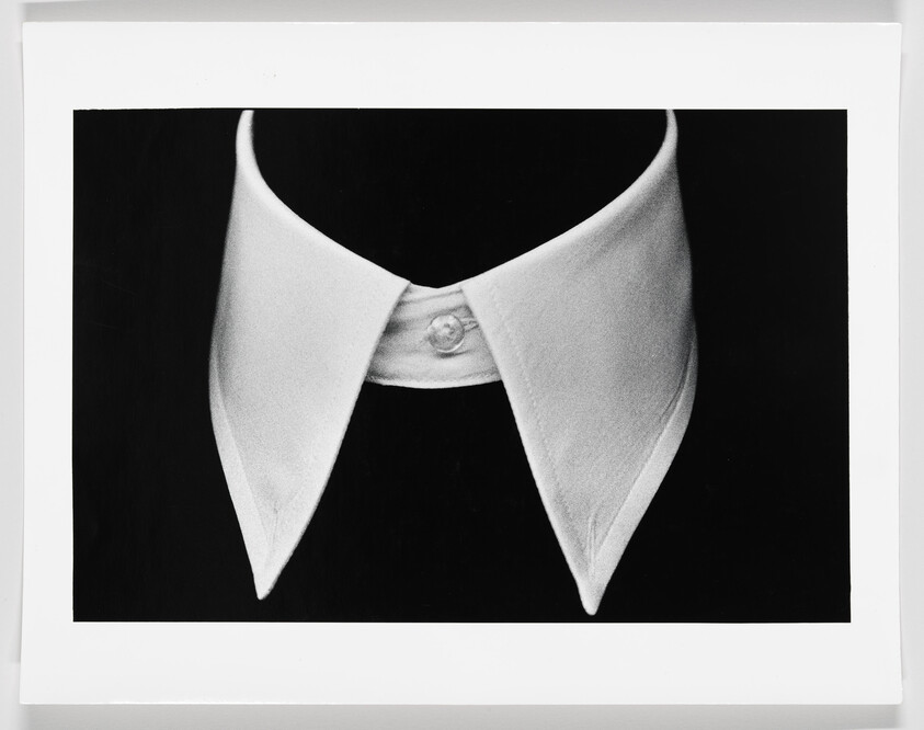 A crisp white detachable shirt collar with pointed tips centered against a black background.